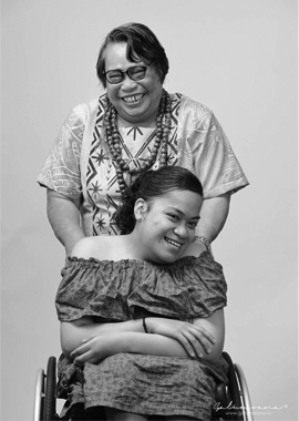 Young lady in her wheelchair with her mother standing behind her